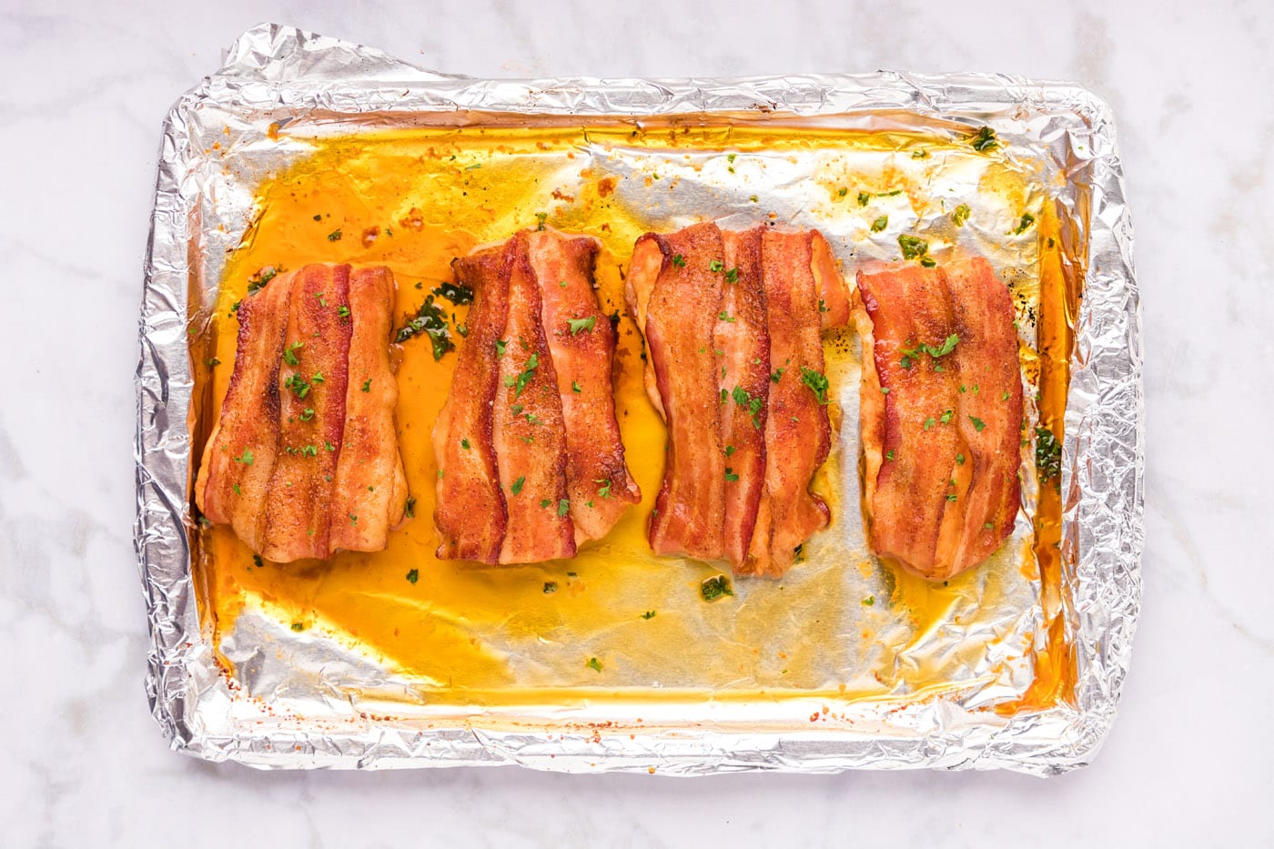 finished bacon wrapped chicken on a baking sheet