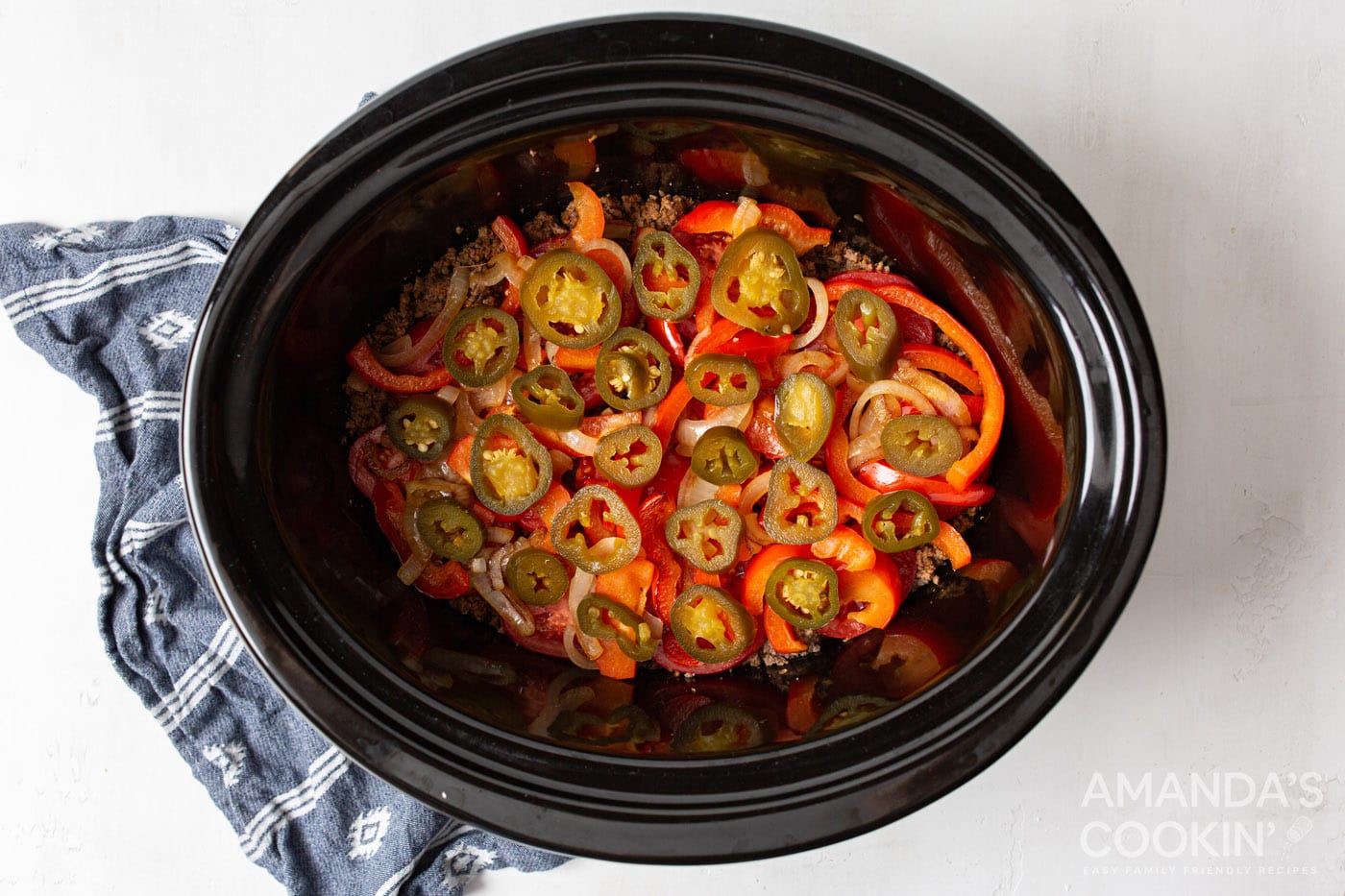 jalepenos on top of tomatoes and beef in crockpot
