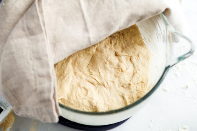 bread dough in bowl with kitchen towel