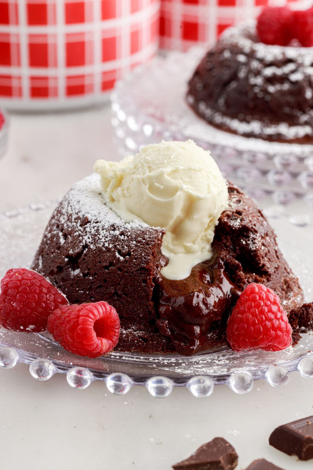 Lava Cake on a plate with raspberries topped with powdered sugar and a scoop of ice cream