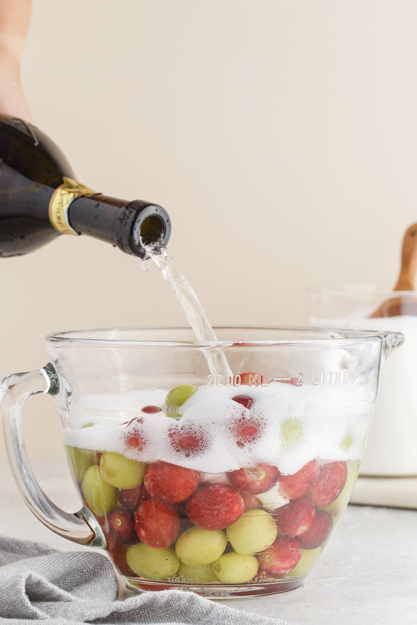 pouring prosecco into a bowl of grapes