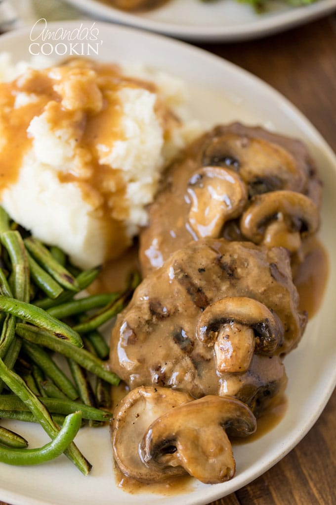 salisbury steak on a plate with mashed potatoes and green beans