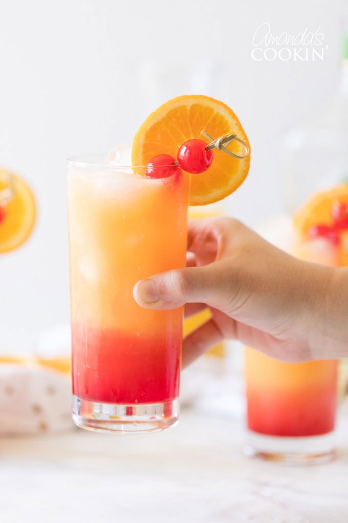 hand holding tequila sunrise drink